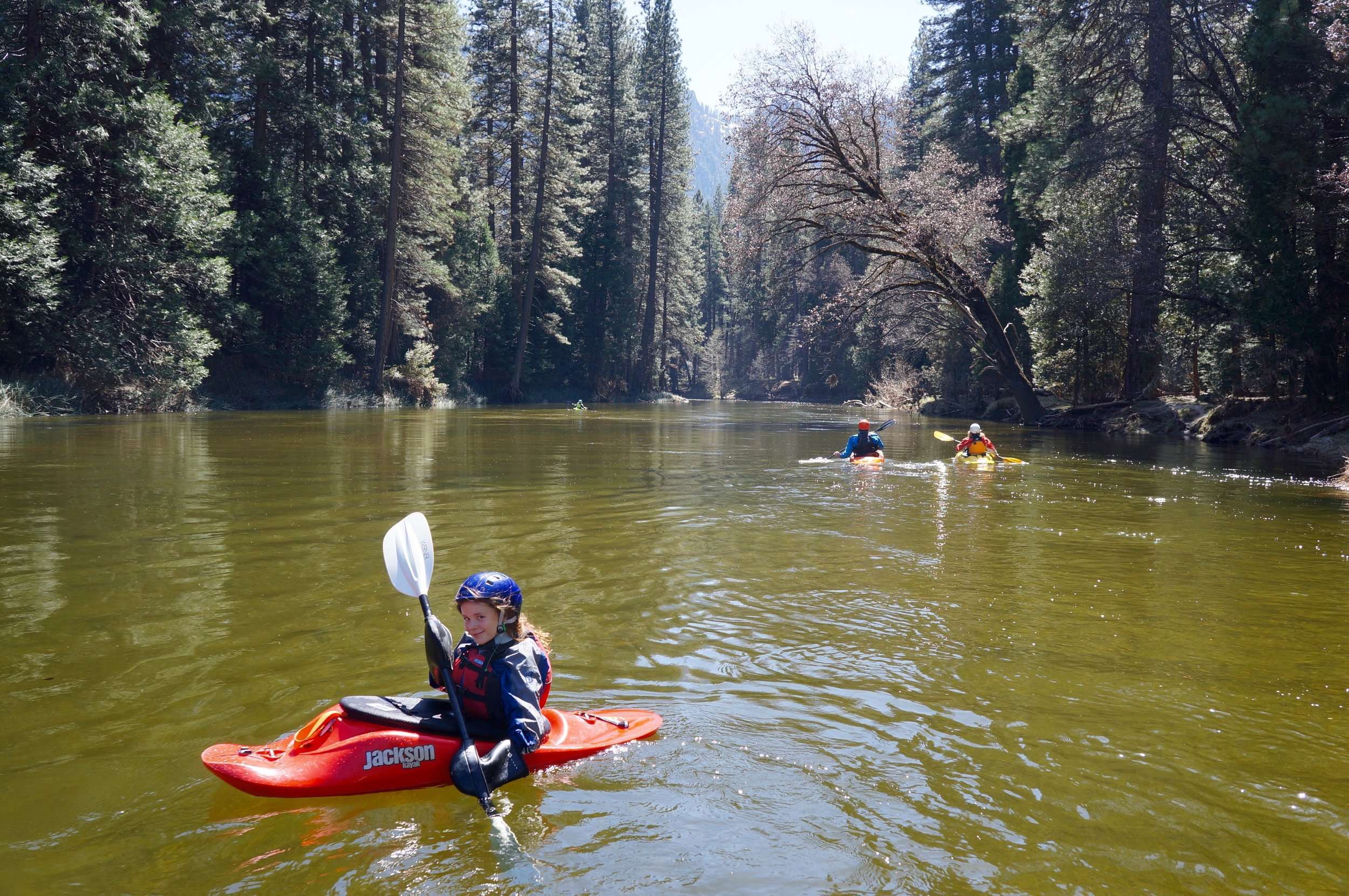 a man riding on the back of a boat next to a lake