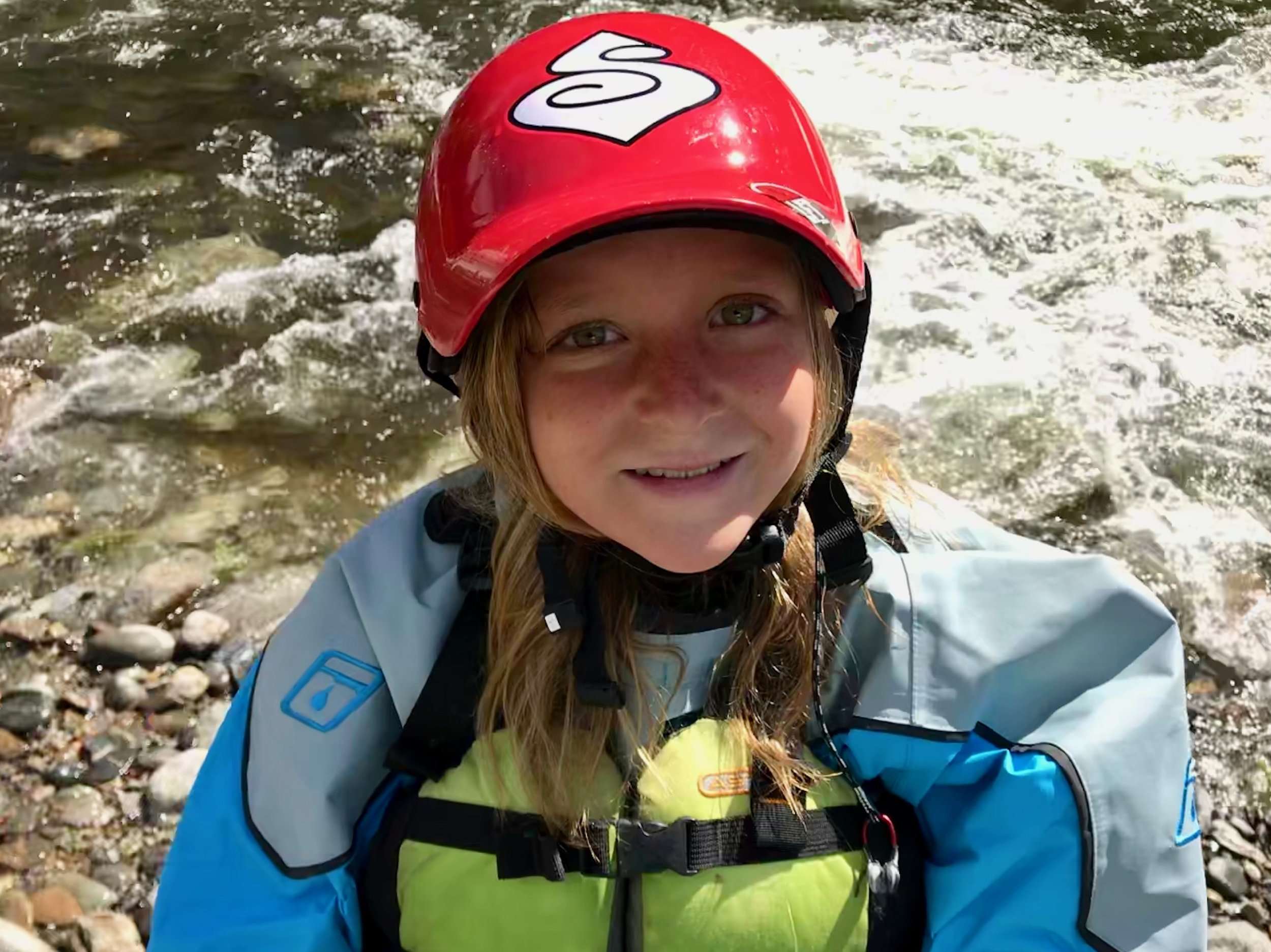 a young boy wearing a helmet smiling at the camera