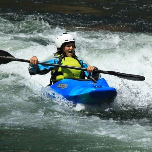 a young girl riding a wave on a raft in a body of water