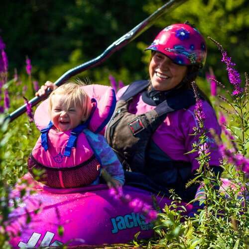 a little girl riding on the back of a pink and purple flowers